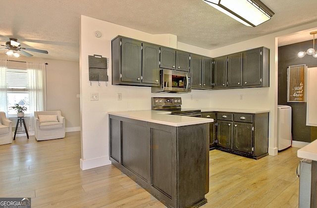 kitchen featuring a ceiling fan, a peninsula, washer / clothes dryer, light wood-style floors, and appliances with stainless steel finishes