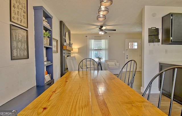 unfurnished dining area with a textured ceiling, light wood-style floors, and ceiling fan