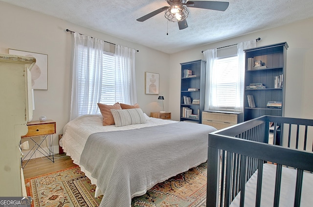 bedroom featuring ceiling fan, wood finished floors, and a textured ceiling