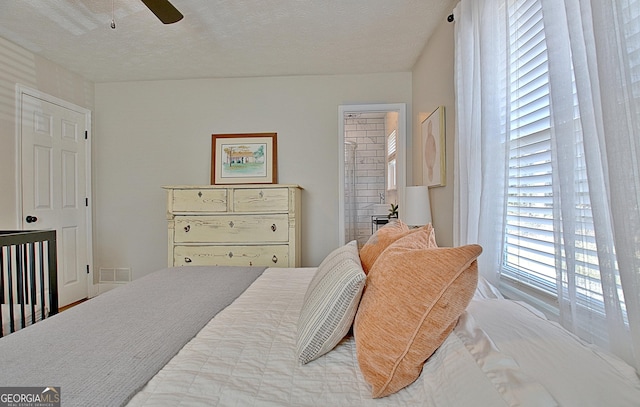 bedroom featuring visible vents, a textured ceiling, ensuite bath, and ceiling fan