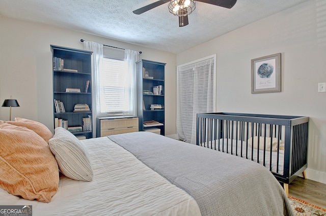 bedroom featuring a textured ceiling, a ceiling fan, and wood finished floors