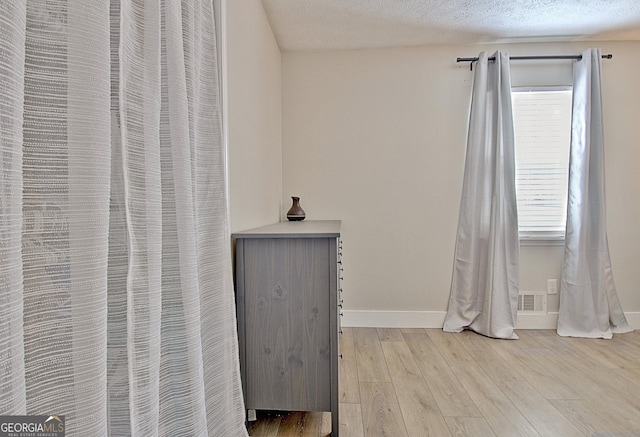 room details with visible vents, baseboards, a textured ceiling, and wood finished floors