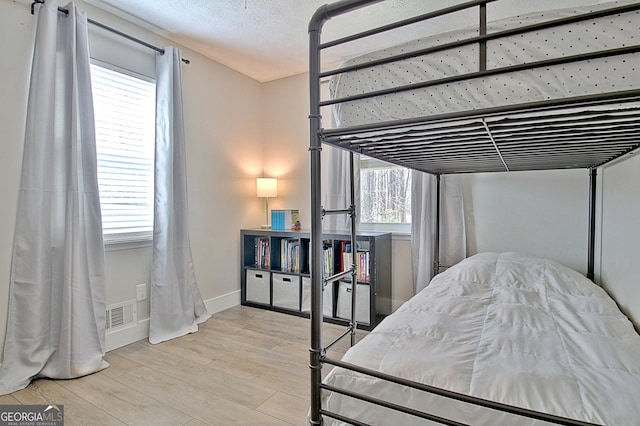 bedroom with visible vents, baseboards, and wood finished floors