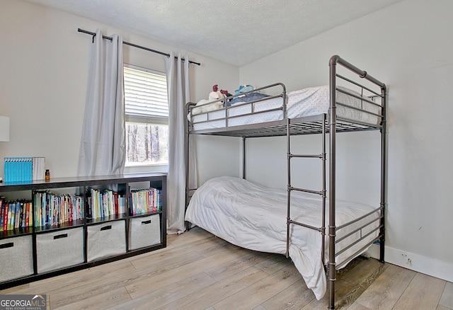 bedroom with a textured ceiling, baseboards, and wood finished floors