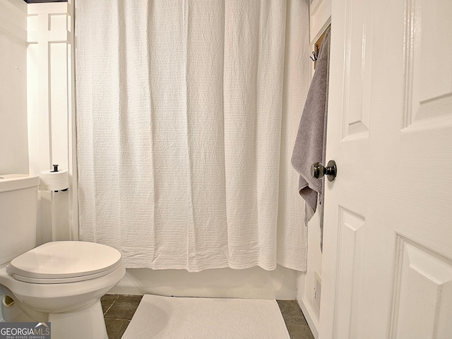 full bath featuring tile patterned floors, shower / bath combo with shower curtain, and toilet