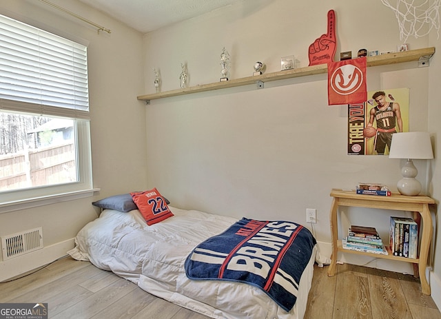 bedroom with wood finished floors, visible vents, and baseboards