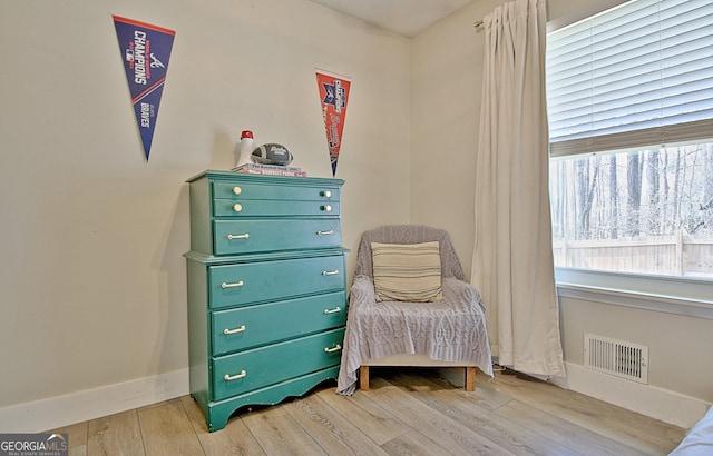 living area with light wood-type flooring, visible vents, and baseboards