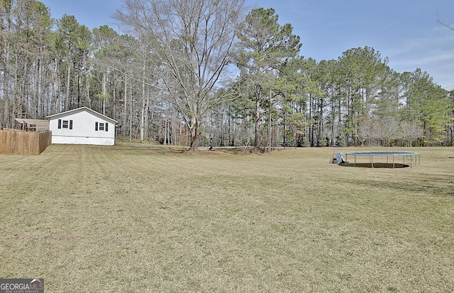 view of yard featuring a trampoline and fence