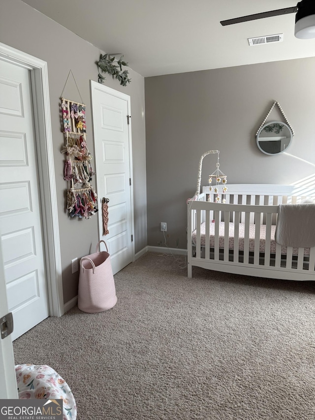 bedroom with a nursery area, baseboards, carpet, and visible vents