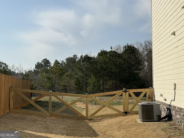 view of gate with cooling unit and fence