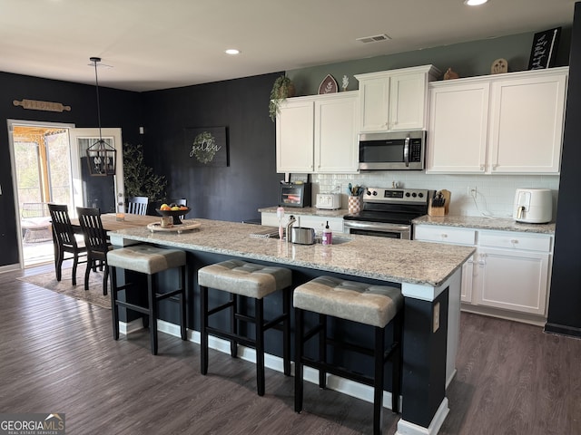 kitchen with tasteful backsplash, visible vents, appliances with stainless steel finishes, and dark wood-style flooring