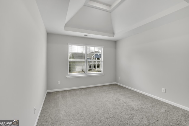 carpeted empty room with a tray ceiling, visible vents, and baseboards