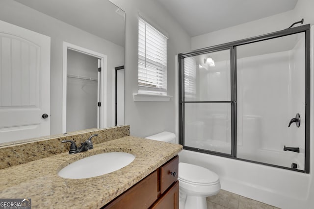 full bath with combined bath / shower with glass door, toilet, vanity, and tile patterned floors