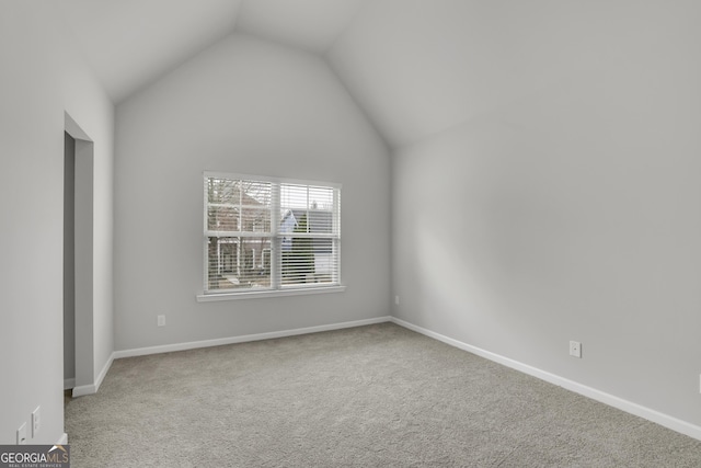 spare room with vaulted ceiling, carpet flooring, and baseboards