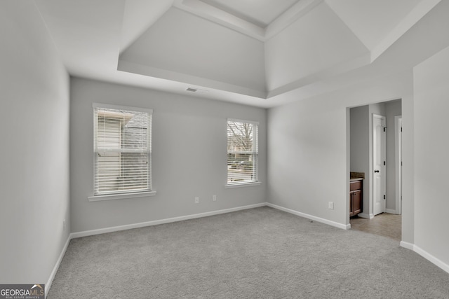 empty room with a tray ceiling, baseboards, visible vents, and carpet flooring