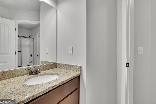 bathroom featuring a shower with shower door and vanity