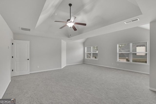 empty room featuring carpet, lofted ceiling, a ceiling fan, and visible vents