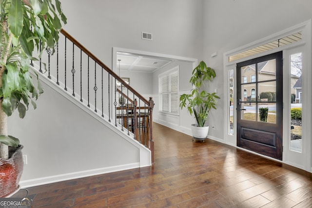 entryway featuring visible vents, wood finished floors, stairway, baseboards, and a towering ceiling