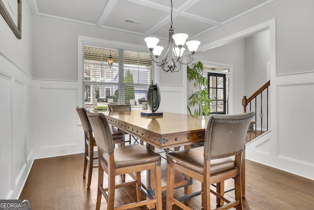 dining room featuring a chandelier, a decorative wall, and coffered ceiling