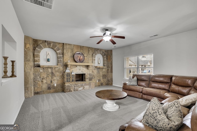 living area with visible vents, carpet floors, a stone fireplace, and a ceiling fan