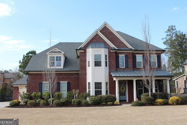 view of front of home with brick siding, covered porch, and a shingled roof