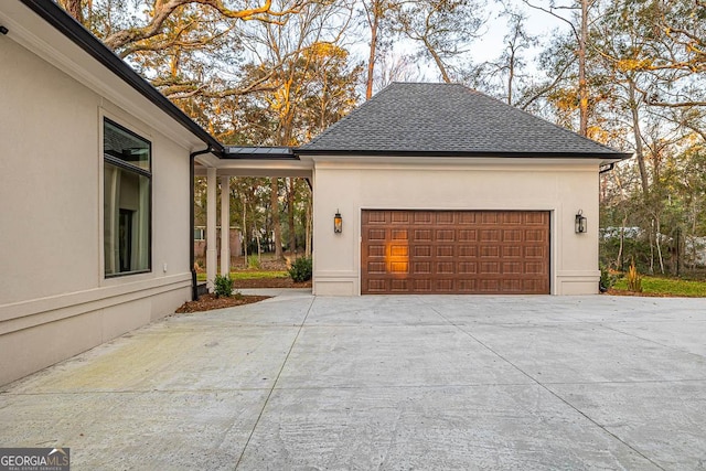 view of home's exterior with concrete driveway, an attached garage, roof with shingles, and stucco siding