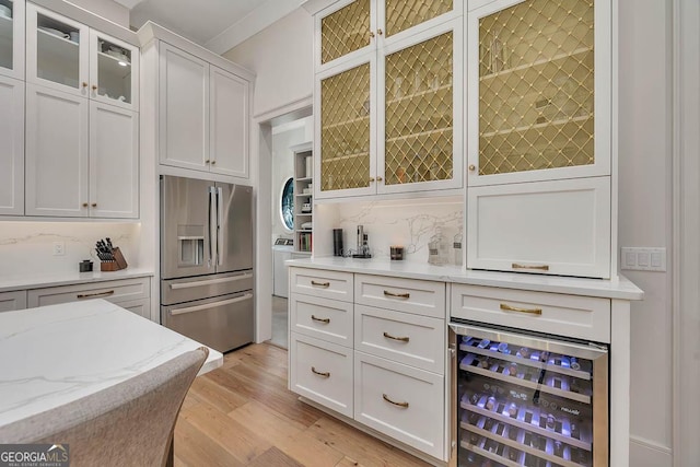 kitchen with beverage cooler, light wood finished floors, stainless steel refrigerator with ice dispenser, white cabinetry, and backsplash