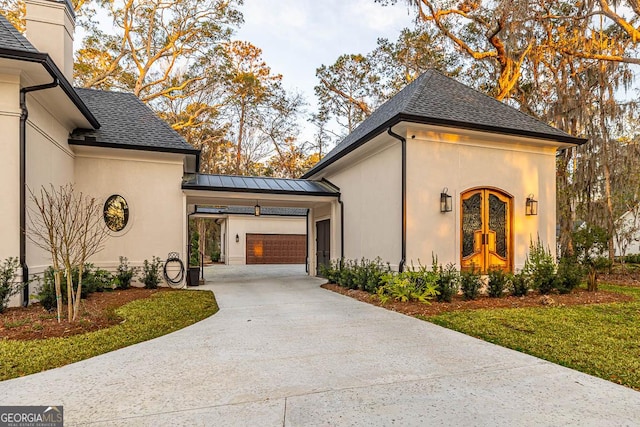 view of property exterior with stucco siding, a garage, driveway, and a shingled roof