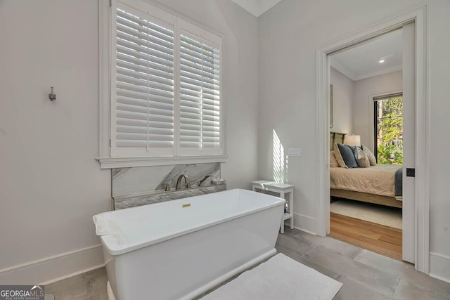 ensuite bathroom with connected bathroom, baseboards, and a soaking tub