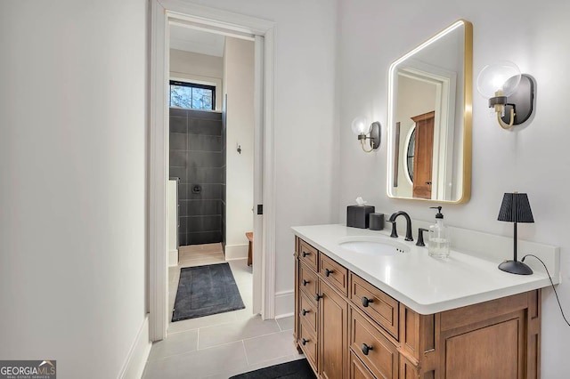 full bath featuring vanity, tile patterned floors, baseboards, and tiled shower