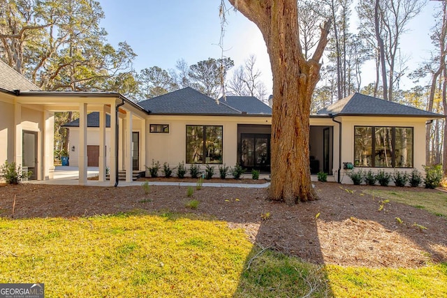 rear view of property with stucco siding and a lawn