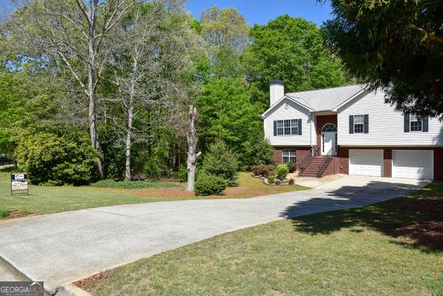 332 Black Willow Ct, Locust Grove, GA 30248 - bi-level home featuring concrete driveway, a chimney, an attached garage, and a front lawn