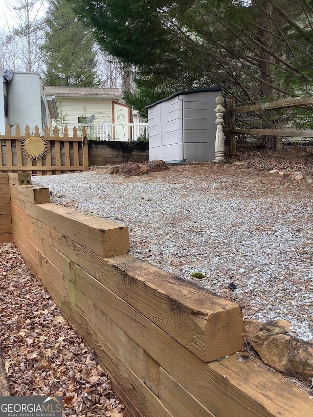 view of yard featuring a shed, an outdoor structure, and fence