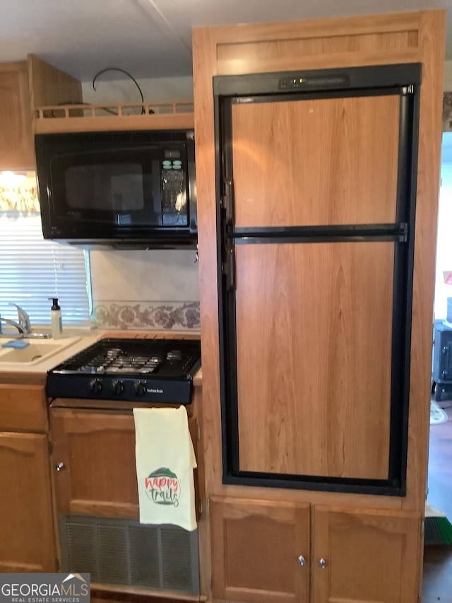 kitchen with stovetop, black microwave, and a sink