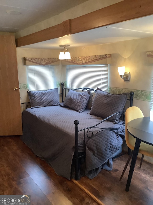 bedroom featuring beamed ceiling and wood finished floors