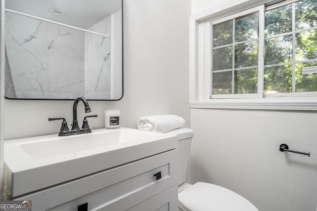 bathroom featuring a marble finish shower, plenty of natural light, toilet, and vanity