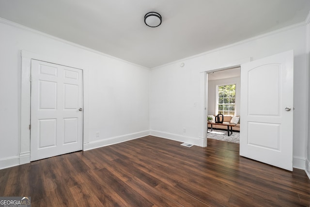 spare room with visible vents, baseboards, dark wood-style flooring, and crown molding