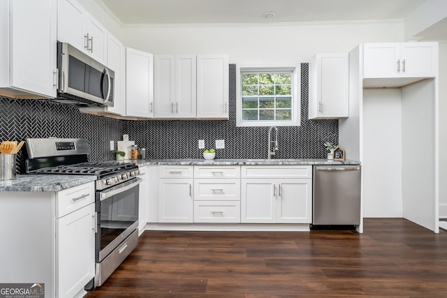 kitchen featuring crown molding, dark wood-style floors, white cabinets, stainless steel appliances, and a sink