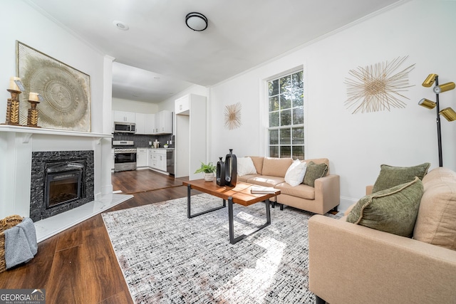 living room featuring dark wood-type flooring, a fireplace, and crown molding