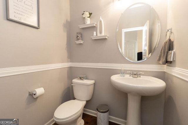 half bathroom featuring a sink, baseboards, and toilet