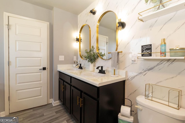 bathroom with double vanity, toilet, wood finished floors, and a sink