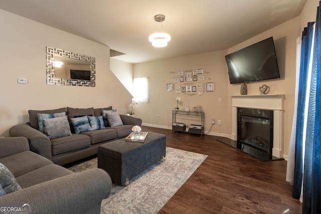 living area featuring a glass covered fireplace, wood finished floors, and baseboards