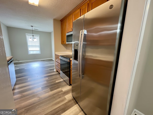 75 Heatherstone Way, Covington, GA 30016 - kitchen with stainless steel appliances, brown cabinets, light wood finished floors, a textured ceiling, and light countertops