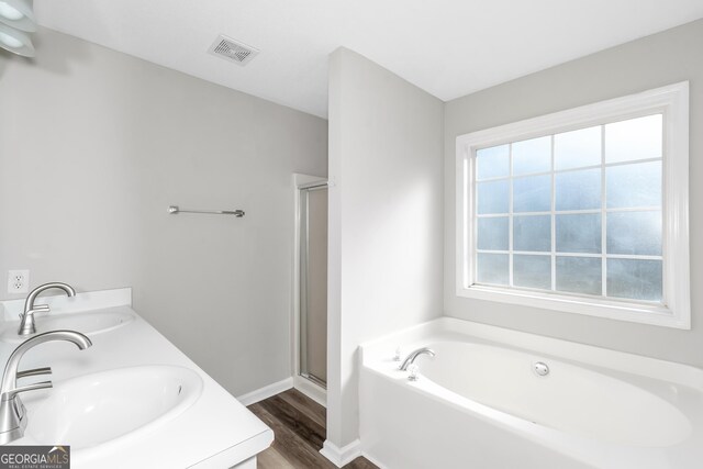 75 Heatherstone Way, Covington, GA 30016 - full bathroom featuring a garden tub, wood finished floors, a shower stall, and double vanity