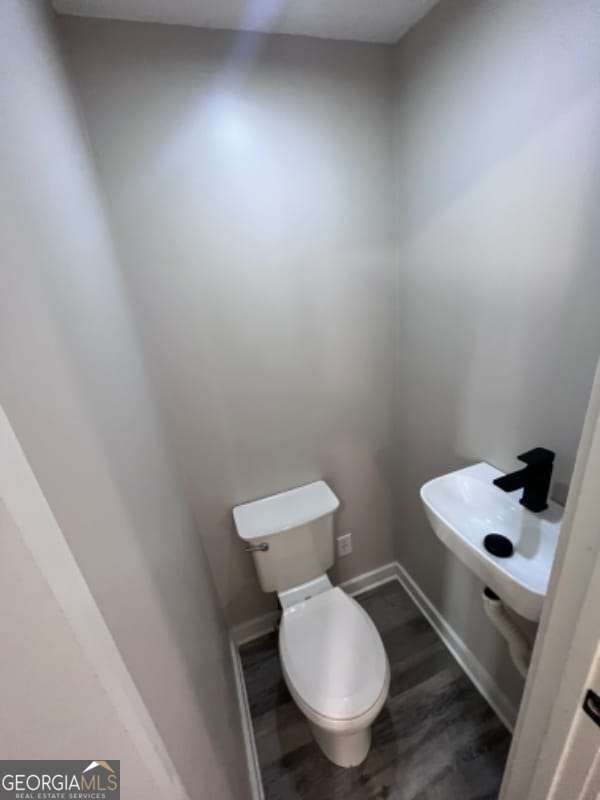 bathroom with toilet, wood finished floors, and baseboards