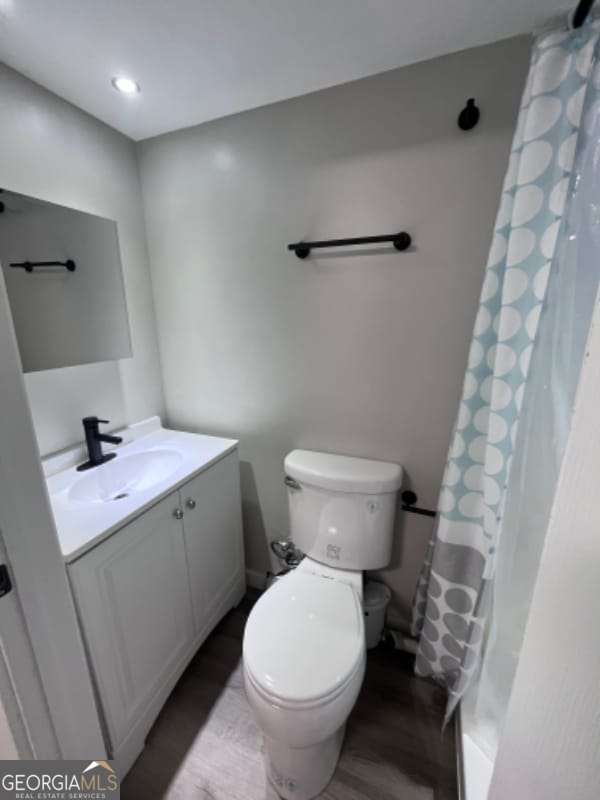 full bathroom with toilet, vanity, a shower with curtain, and wood finished floors