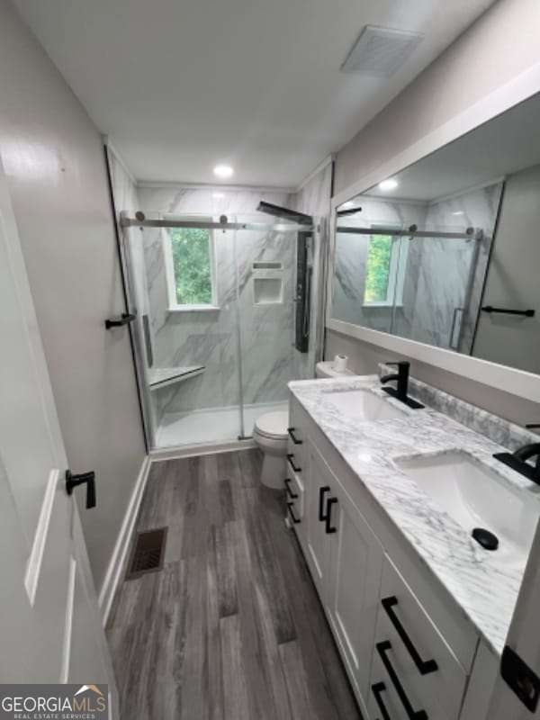 bathroom with wood finished floors, toilet, visible vents, and a sink