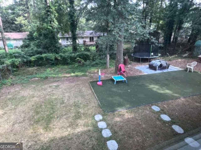 view of yard with a trampoline and a patio area