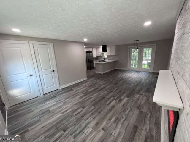 unfurnished living room featuring recessed lighting, baseboards, dark wood-style flooring, and a textured ceiling