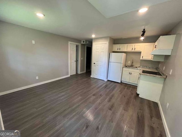 kitchen with white cabinets, baseboards, freestanding refrigerator, and a sink